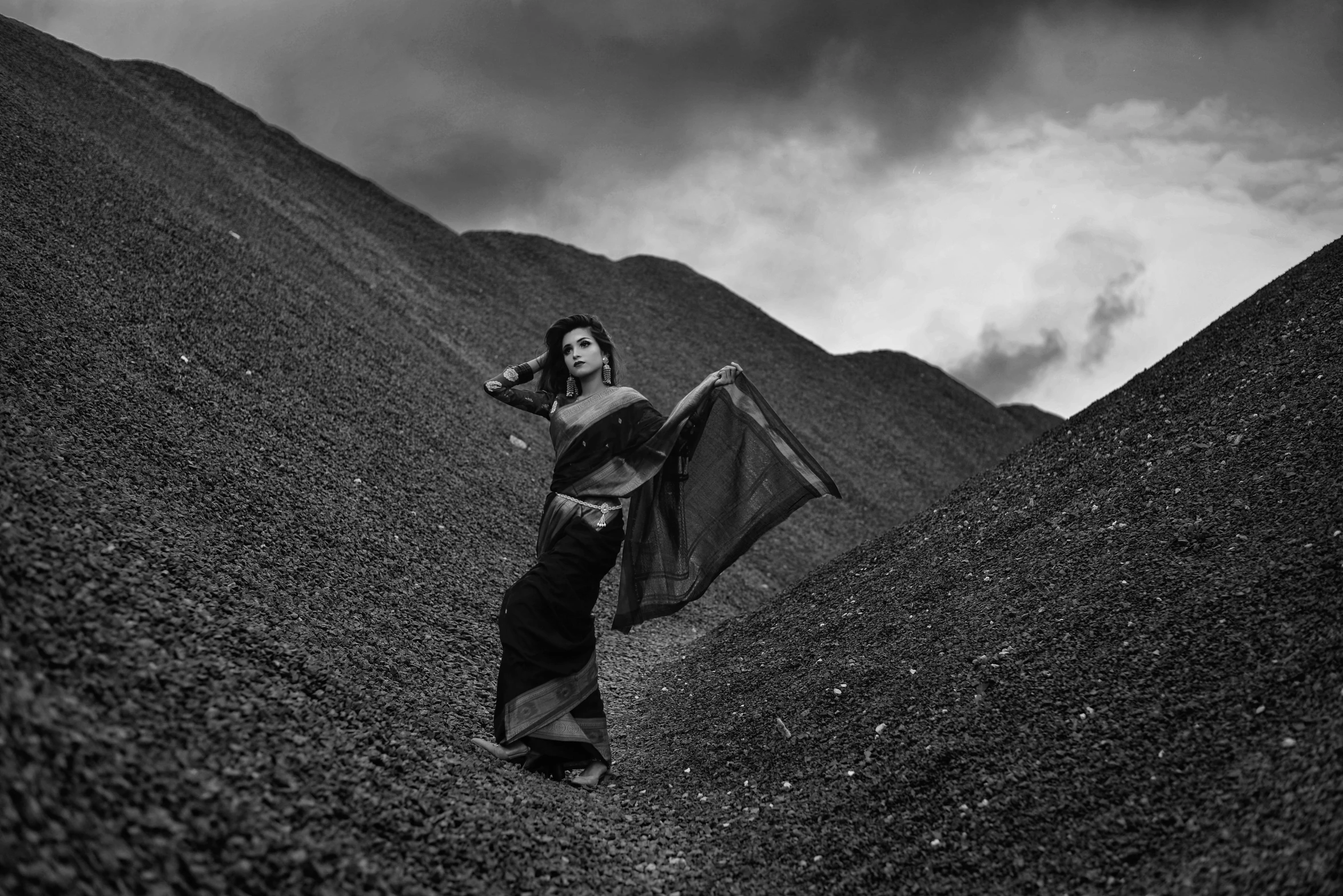 a woman wearing a black and white sari walking up a hill