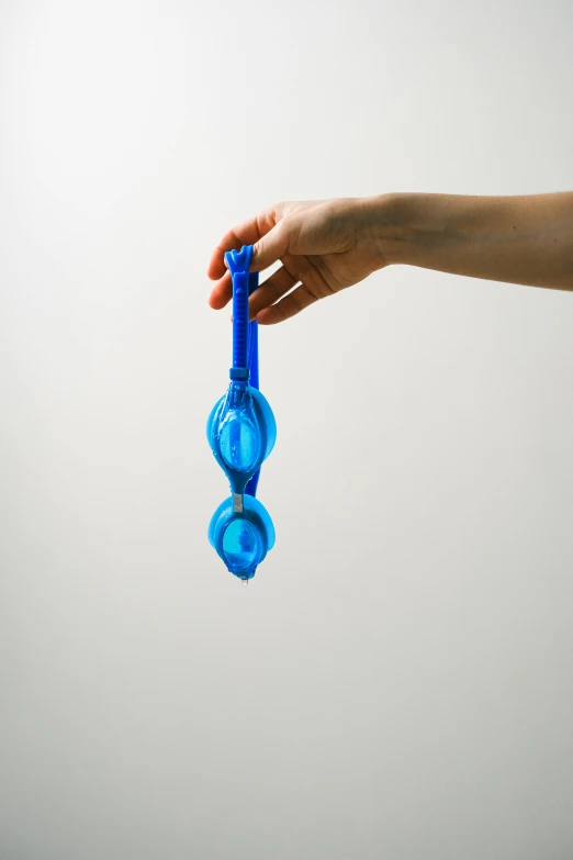 a hand holding a blue toy that looks like two wheels