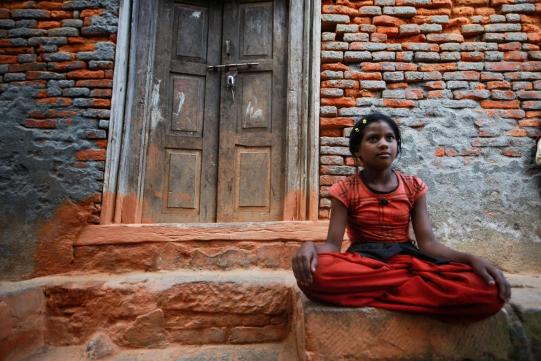 an indian woman sitting in front of an open doorway
