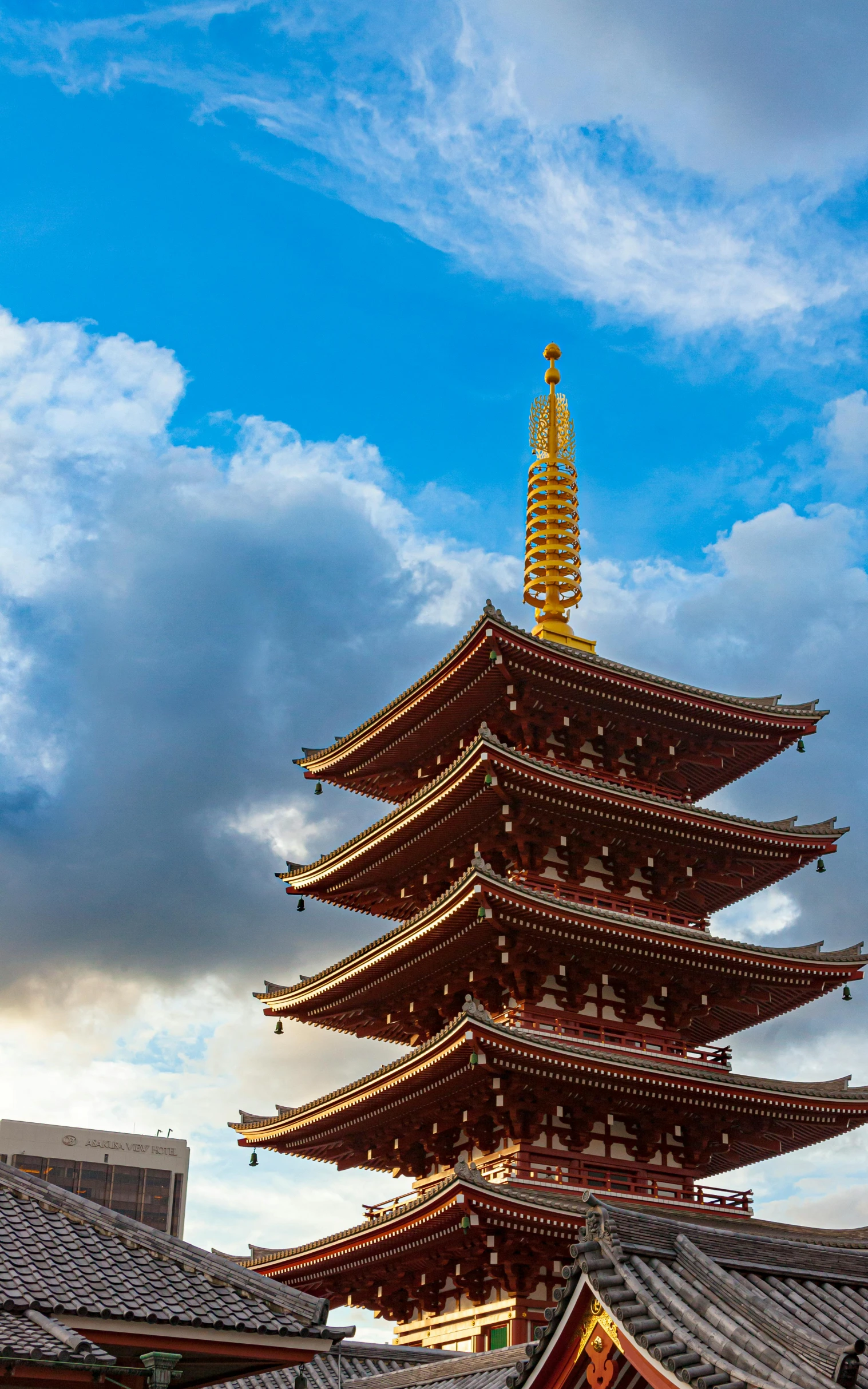 a tall building with an orange top against a cloudy sky