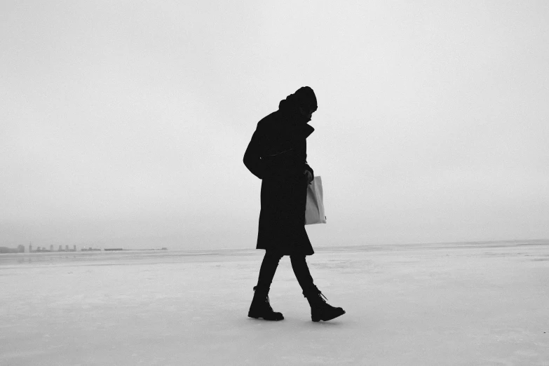 woman walking down snow covered ground in black coat