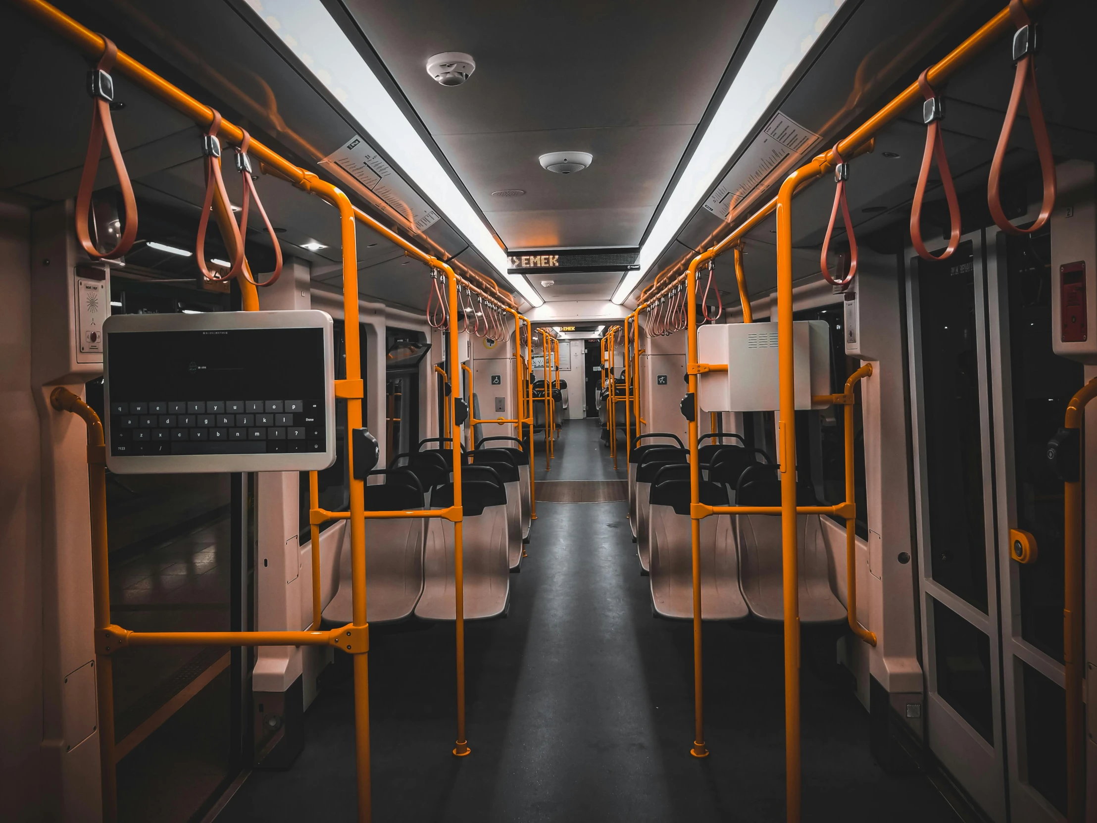 the inside of a commuter train, with many empty seats and rails