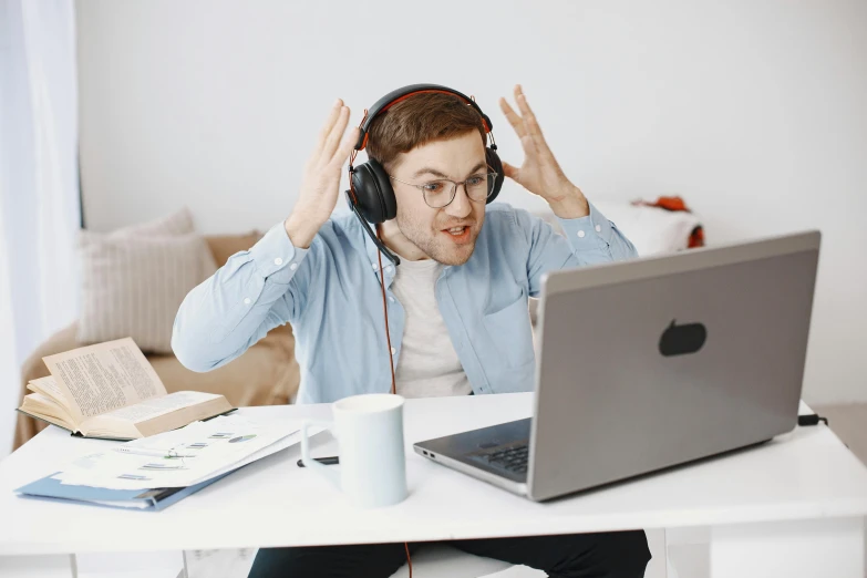 a man sitting at a desk with his hands up while listening to music