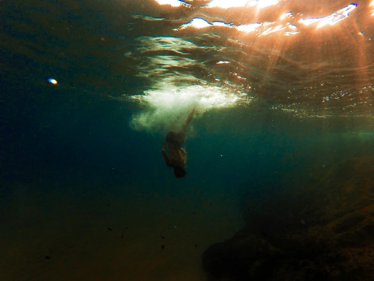 a woman swimming underwater near the bottom of a body of water