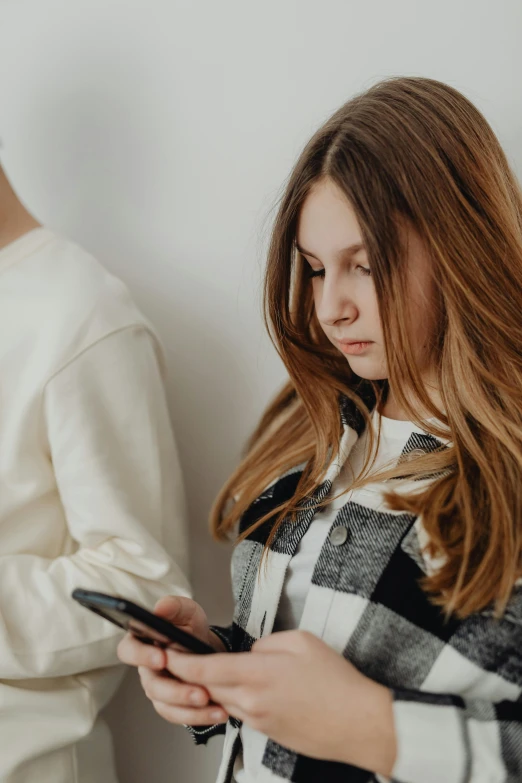 a girl uses a cellphone and looks at her dress