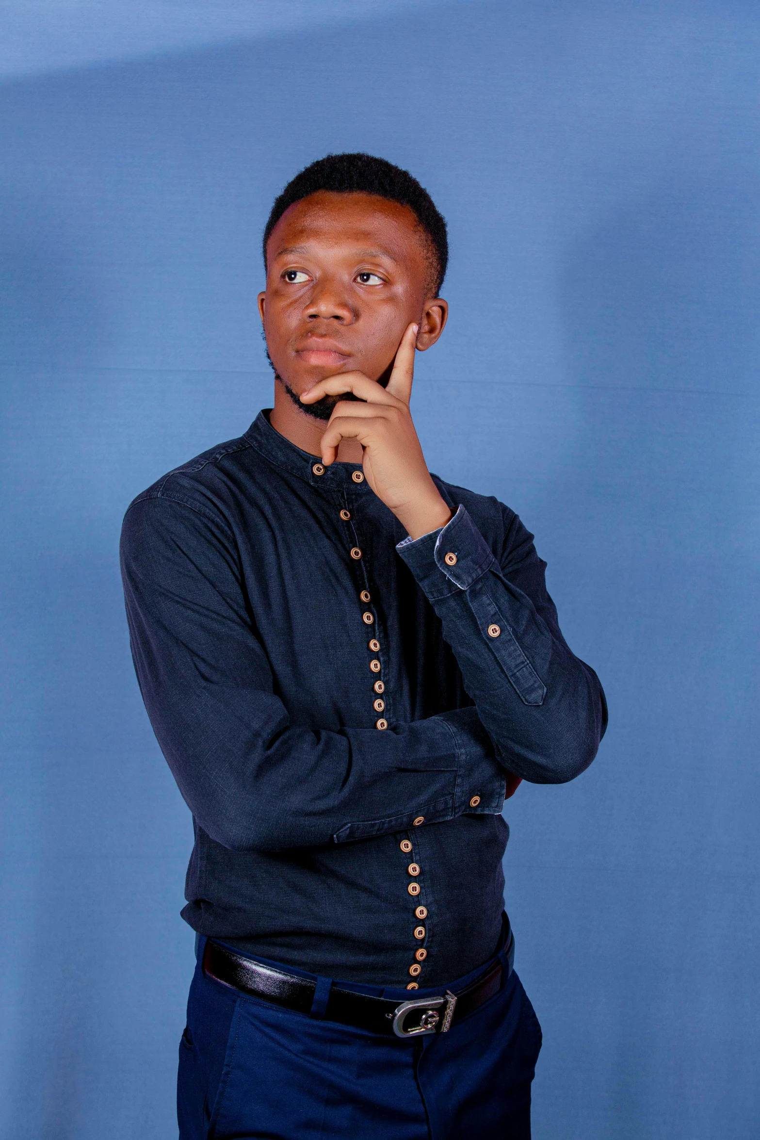 a young man in a dark blue shirt poses for the camera