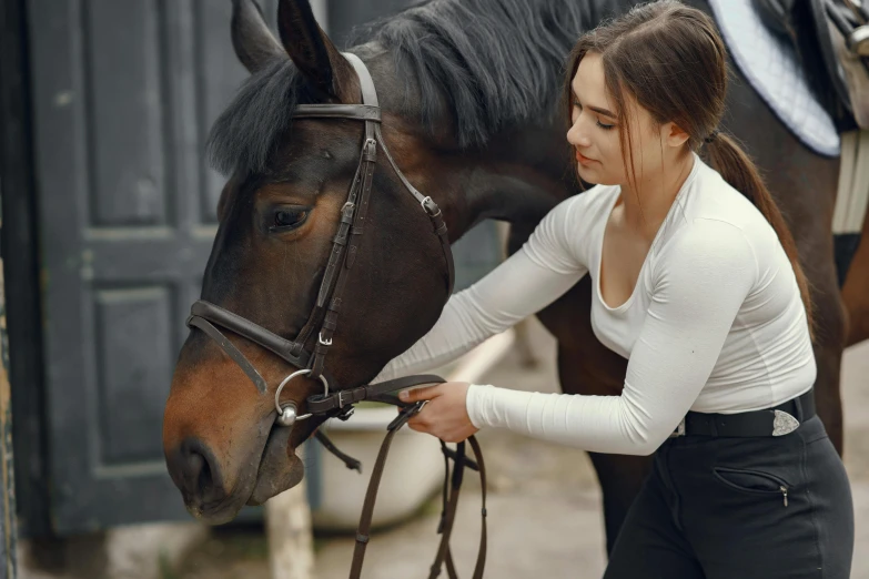 a woman touching the bridle of a horse