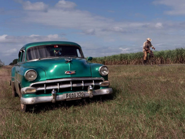 an old green car in a grassy field