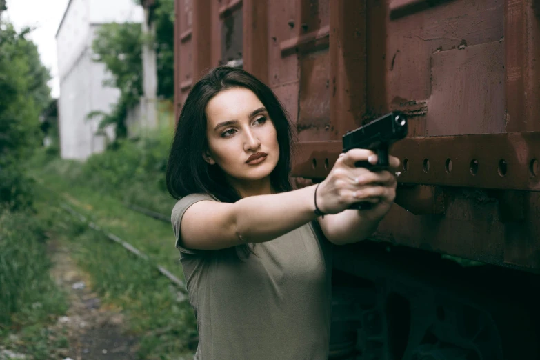 a woman in brown shirt pointing a gun at camera