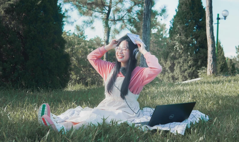 a woman sitting on the grass, wearing a veil and holding her head to her hair