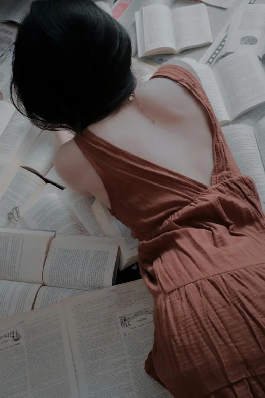 a woman with long dark hair laying on top of open books