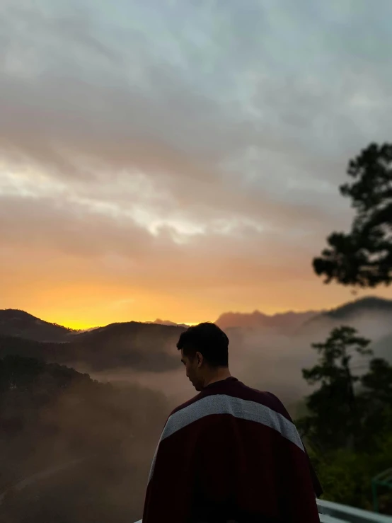 a man looking at the mountains as the sun sets