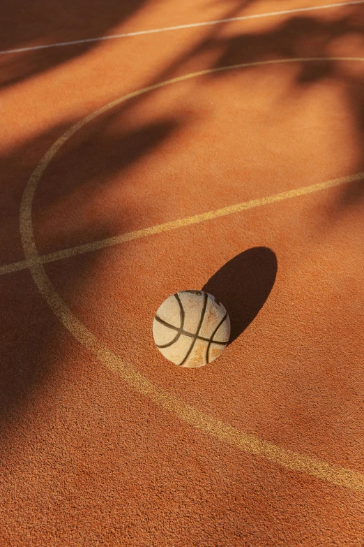 a ball on the court that is in front of a tree