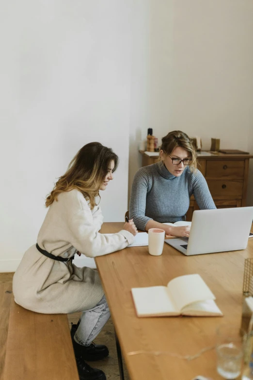 two people sitting at a table with a laptop