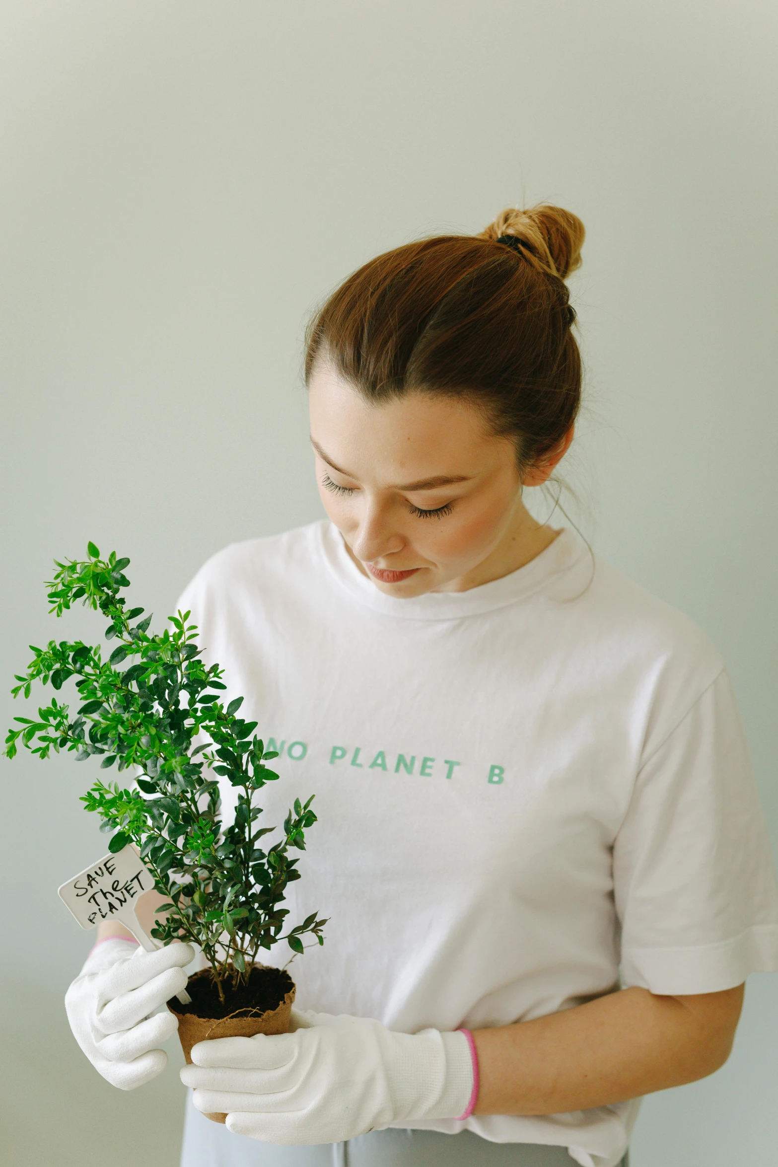 the girl is holding a green plant with gloves on