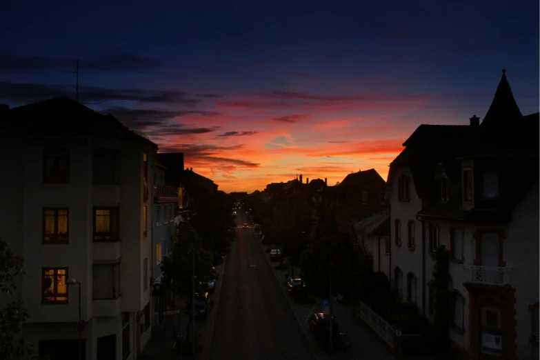 a street in the dusk with buildings and a clock tower in the distance