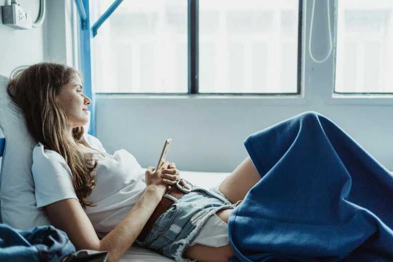 a woman sitting on a bed while looking at her cell phone