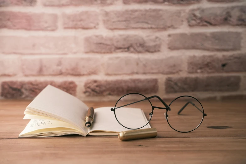 an open book is shown next to a pair of reading glasses