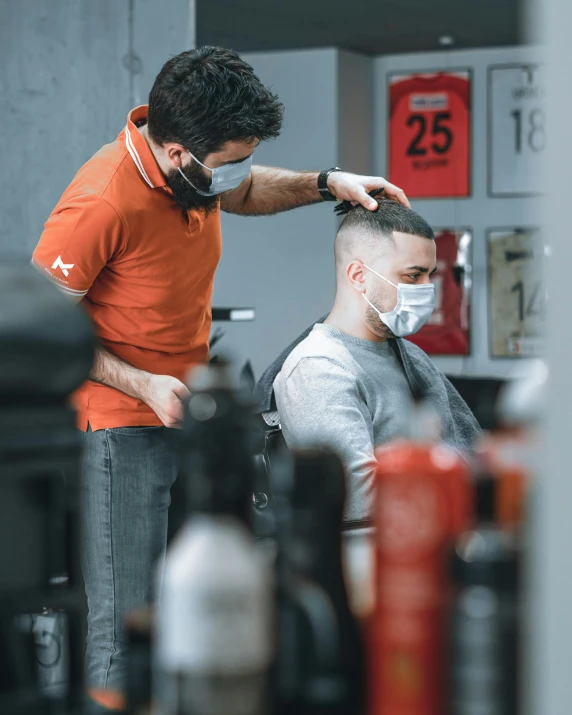 two men are getting their hair trimmed at the barber shop