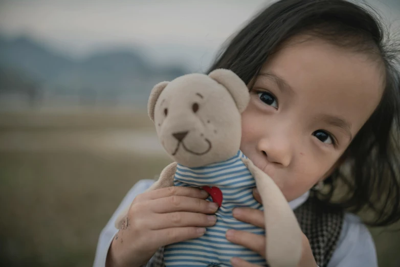 there is a little girl holding a stuffed bear