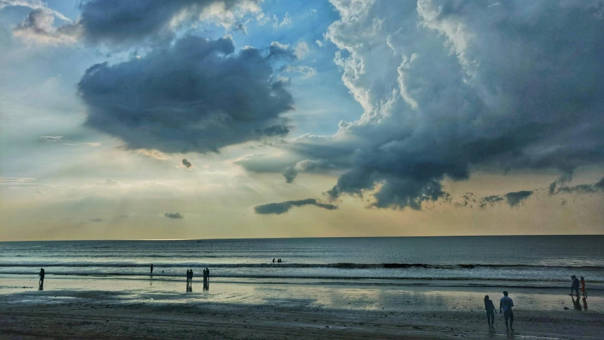 many people are standing on the beach and watching the sun