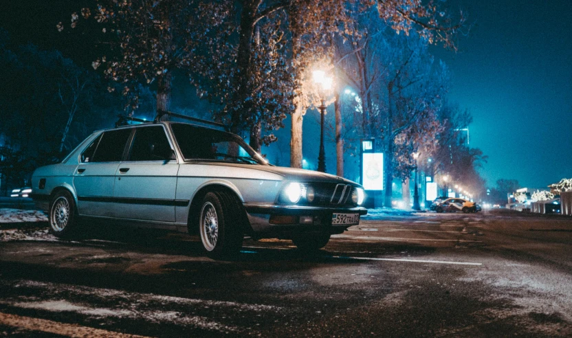 an old - fashioned white car sits parked in a dark city street