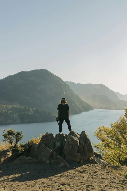 a person that is standing on rocks next to a lake