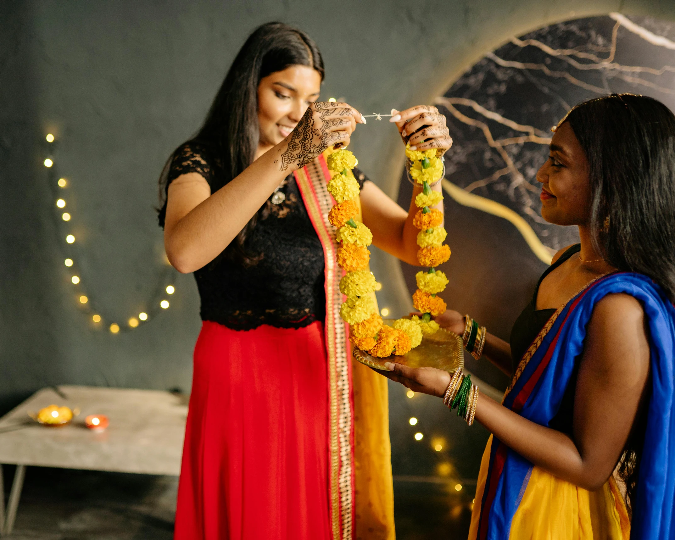 two girls dressed in indian garb with yellow flowers