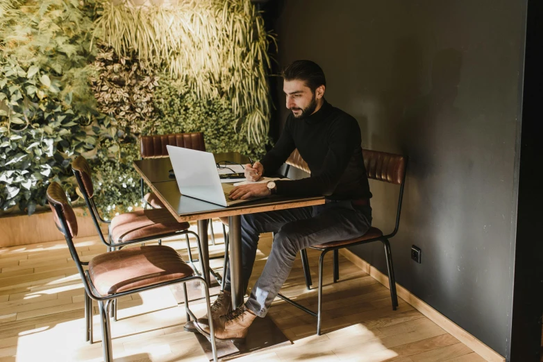 a man working on his computer at a small desk