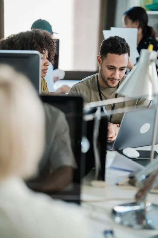 a man working on his laptop with other people