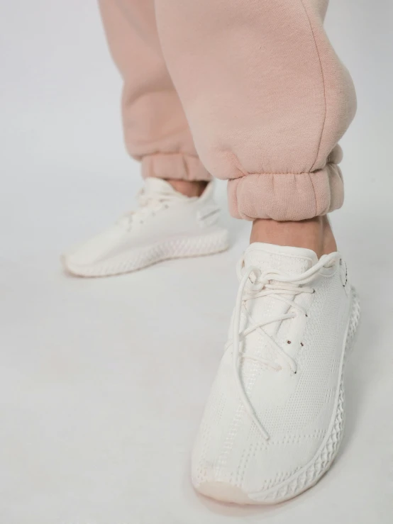 a close up of the white sneakers and pants on someone