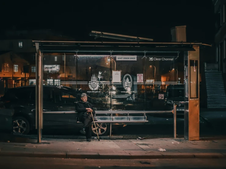 a man sitting in front of a glass covered shelter