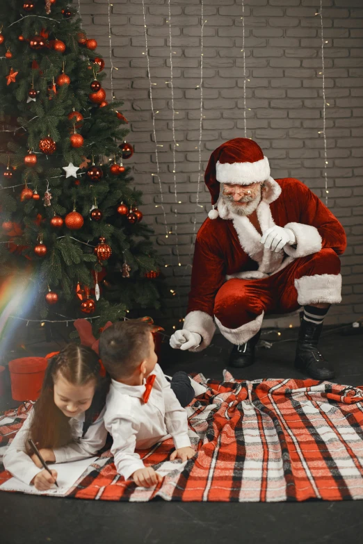 a man in a santa suit putting wrapping paper around a child on a floor