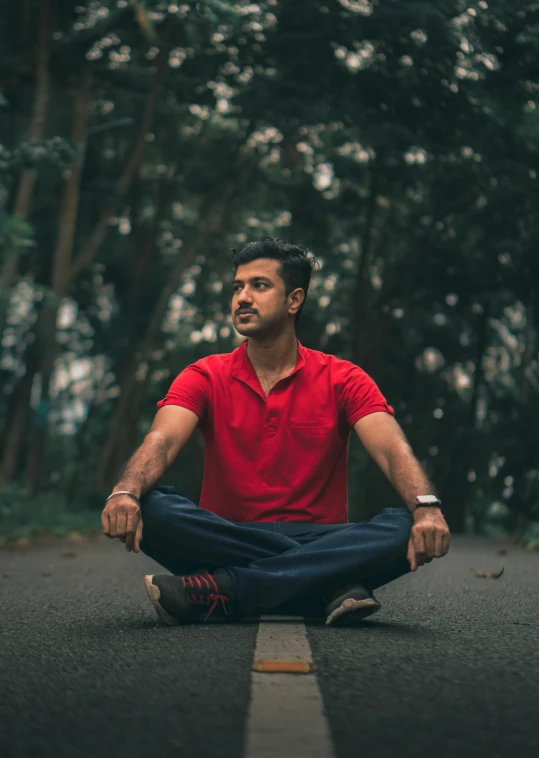 a man sitting on the street in front of trees