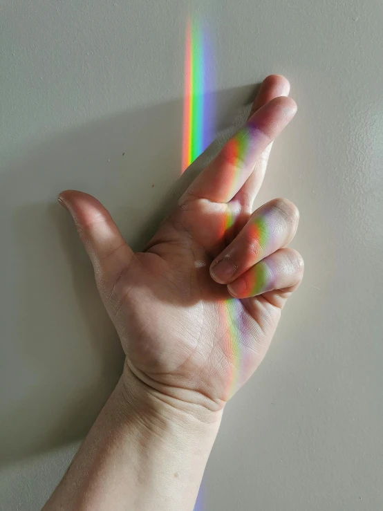 someone holding their hand out with some rainbow shining in the background