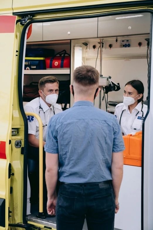 two men and woman are entering a yellow rescue truck