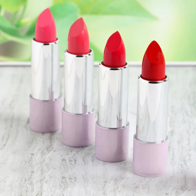 four lipsticks sitting on top of a table with the lids off