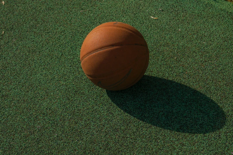 a very shiny brown ball sitting on top of some artificial grass