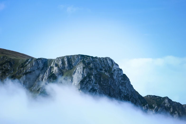 mountains covered in fog under a bright blue sky