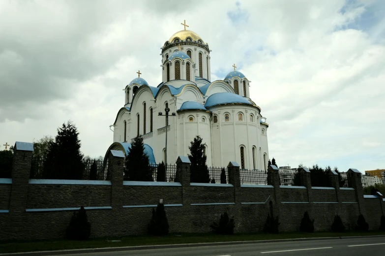 an ornate white building with blue domes in front of a cloudy sky