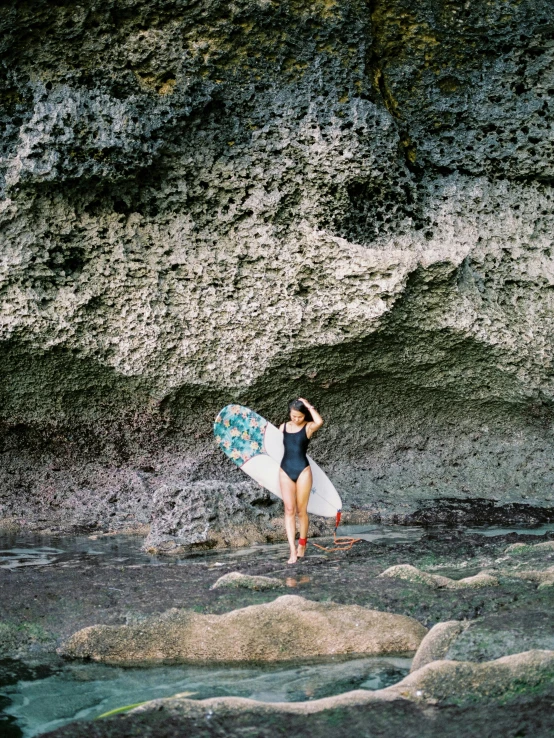 a young woman holding a surf board while standing on top of a beach