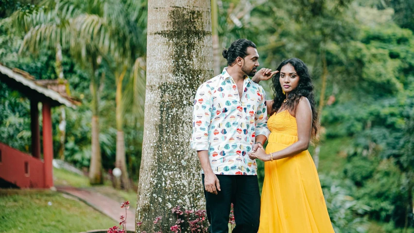 a woman and man in a dress next to trees