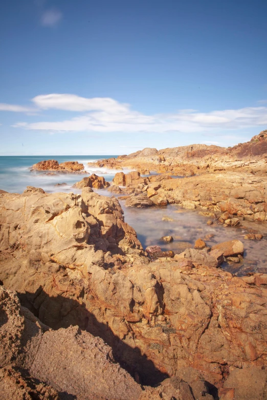 a rocky shoreline line with small waves in the ocean