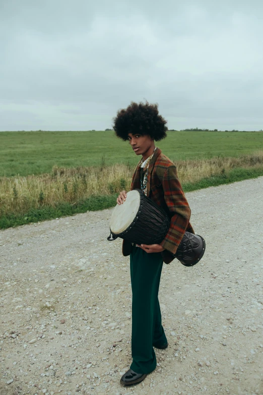 a young man standing on the side of a gravel road holding a frisbee