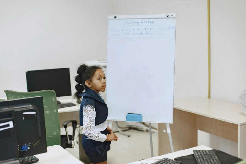 a little girl in shorts holding her hand to a board