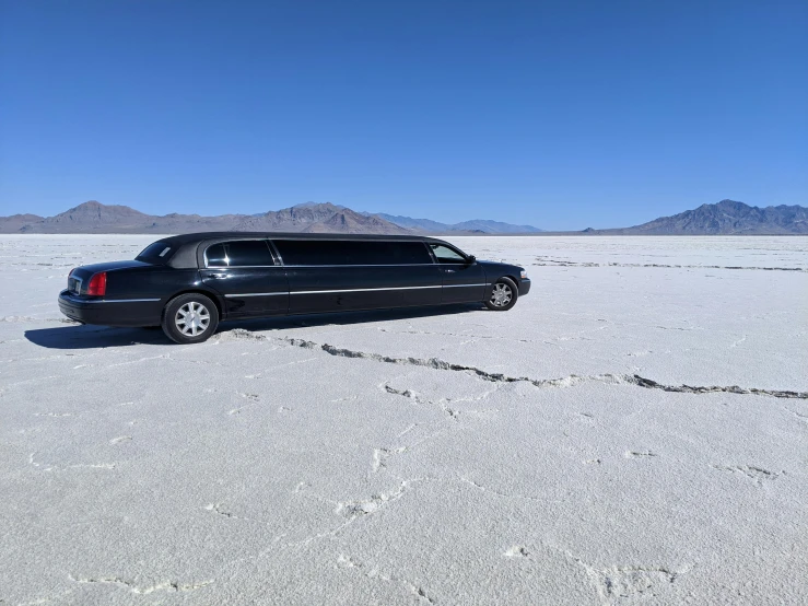 the black vehicle is driving in a vast empty desert