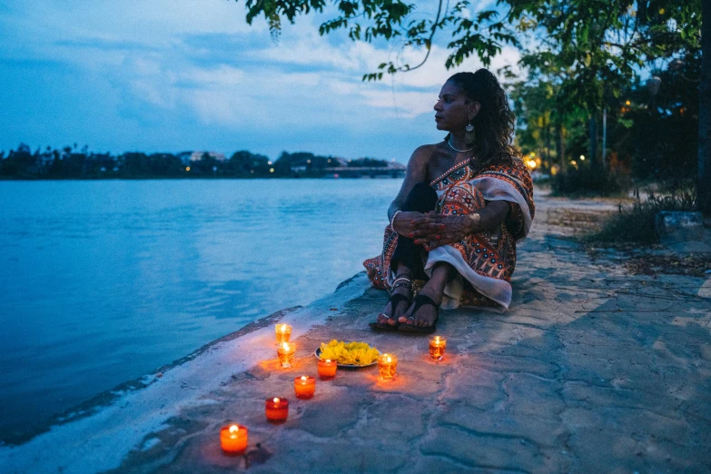 a woman sitting on the edge of a body of water