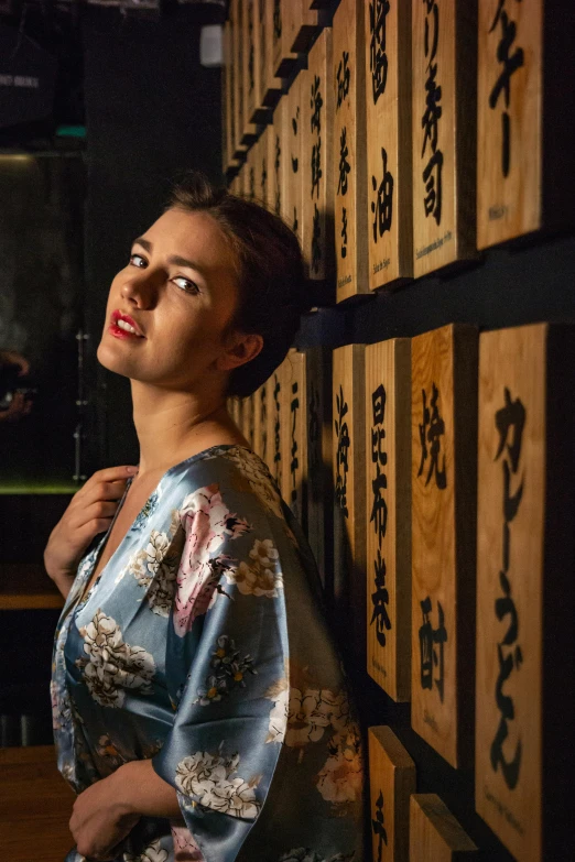 woman in colorful kimono standing in front of two wooden boards