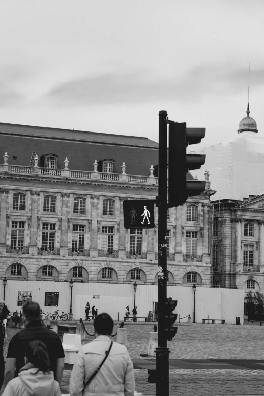 two people walk towards an old building and pedestrian traffic light