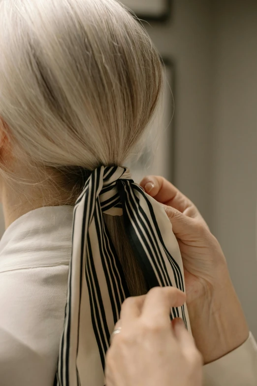 an older woman is putting on her hair and scarf